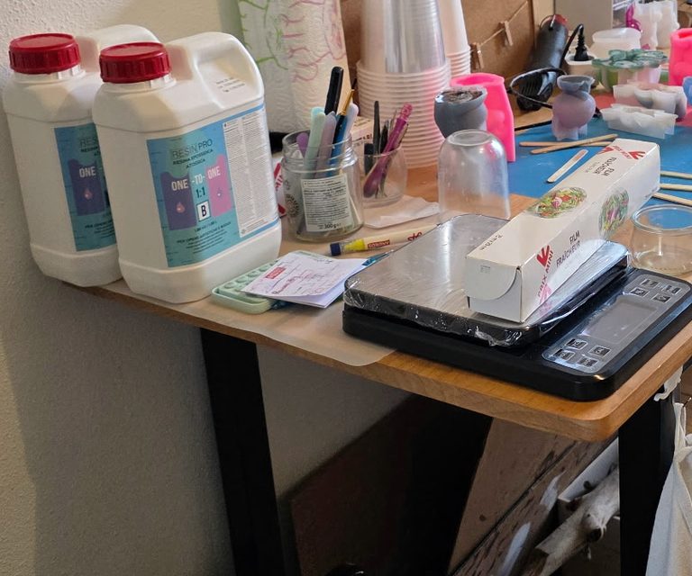 Dosage de la résine époxy à la balance de précision, gobelets et bâtonnets sur le plan de travail de l’atelier de Saujon