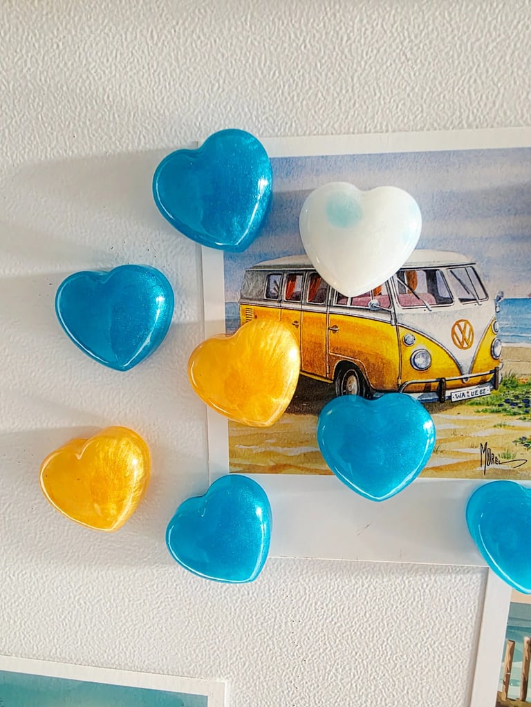 Magnets cœurs en résine bleue, blanche et dorée sur un mur